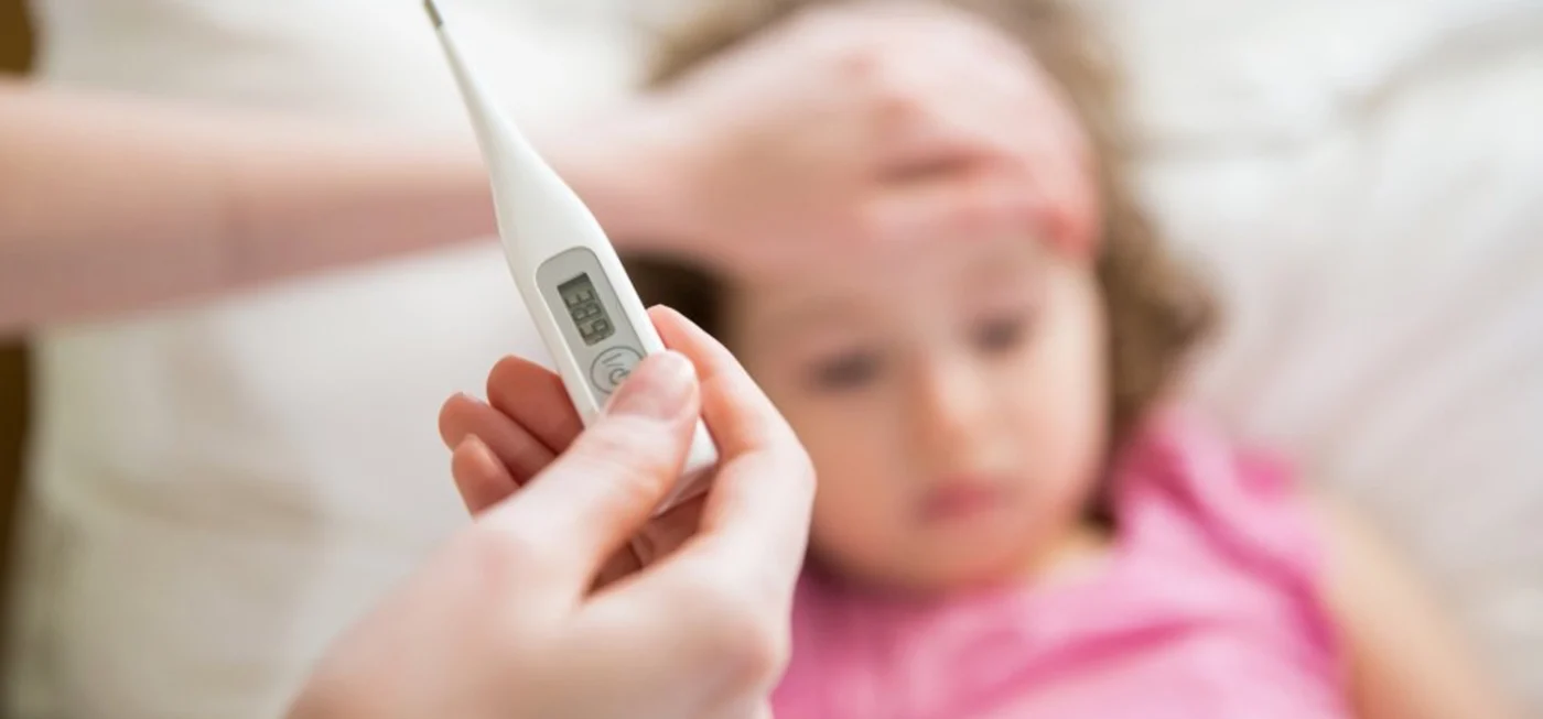 Thermomètre frontal - Thermomètre affichant la température d’un enfant malade, avec une main posée sur son front.