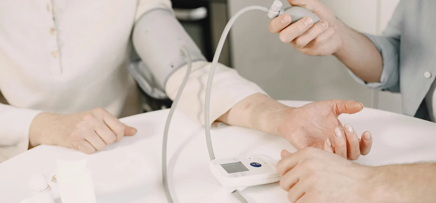 Comment utiliser un tensiomètre correctement pour des résultats fiables ? 3 Une personne utilise un tensiomètre manuel avec brassard pour mesurer la pression artérielle d’un patient.