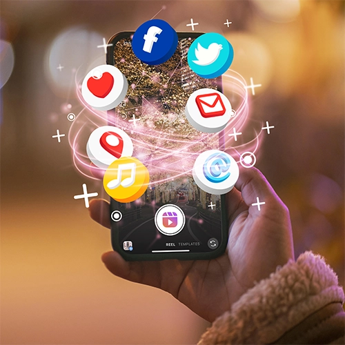 Contact 1 Réseaux sociaux - Une main tenant un smartphone sur lequel des icônes de réseaux sociaux (Facebook, Twitter, email, localisation, musique, et une icône générique de plateforme de médias) flottent autour de l'écran, reliées par des lignes lumineuses roses. L'écran du téléphone affiche une image abstraite ou une scène de ville nocturne avec des lumières. L'arrière-plan est flou, suggérant une profondeur de champ, et on peut distinguer des lumières de ville.