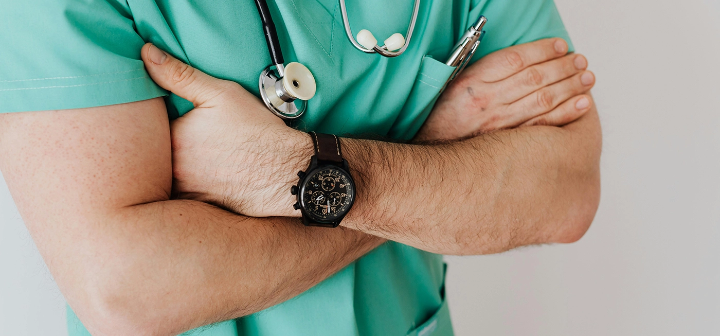 À 51 ans, elle croyait que ses douleurs aux oreilles étaient dues à une infection, mais il s’agissait en réalité d’un cancer rare 3 Médecin en blouse verte avec stéthoscope, bras croisés.